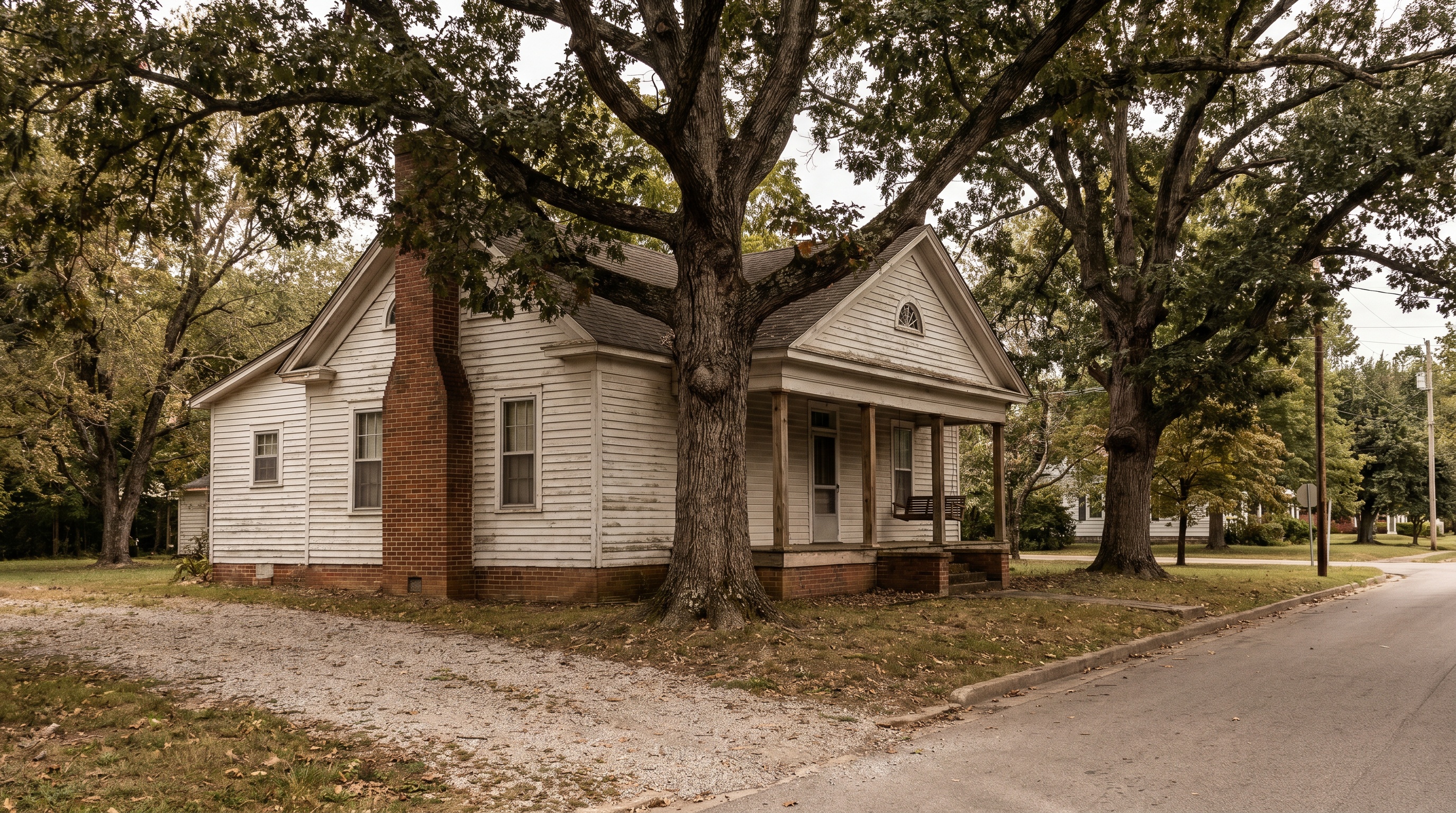 A small-town Kentucky clapboard home with a front porch, mature trees, mid-morning daylight.